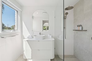 A modern bathroom with a large window, a freestanding bathtub, and a vanity with a sink and mirror. - Hidden Gem, Sauna, Pet-Friendly! (Arrawarra Headland)