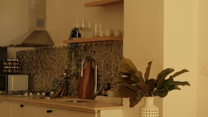 Een keuken met een eettafel gedekt voor twee personen, een gootsteen en een kookplaat.