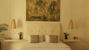Een slaapkamer met een groot bed, een plafondventilator, een schilderij, nachtkastjes en een kamerbreed tapijt met een patroon.