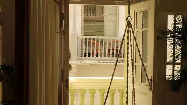 Een kamer met een hangstoel, een balkon met een leuning en een vloer met een patroon.