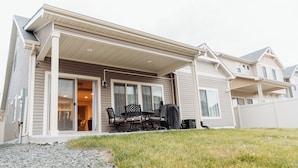 A residential house with a covered patio, a dining area with outdoor furniture, and a visible garage. - Den Haven 15 Min From DIA 3 En Suite Bedrooms (Denver)