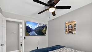 A bedroom with a bed, a ceiling fan, a mounted TV, and a framed picture on the wall. - Charming 3-bedroom house in excellent Troy with AC (Troy)