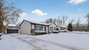 A residential area with a house, a garage, and a driveway covered in snow. - Charming 3-bedroom house in excellent Troy with AC (Troy)