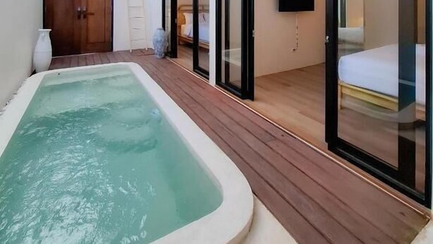 Een moderne spa met een jacuzzi, houten terras en glazen ingerichte ruimtes.
