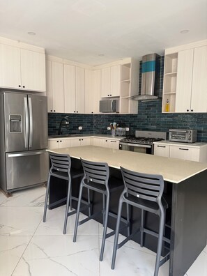 A modern kitchen with a central island, stainless steel appliances, and a tiled backsplash. - Beach Front Spacious 5-bedroom house in lovely Costa del Sol (Costa del sol)