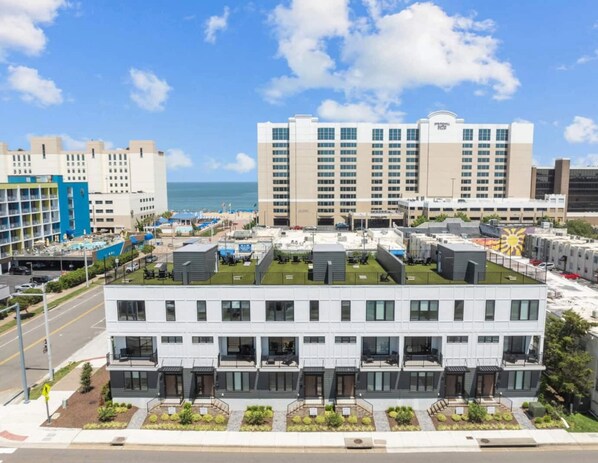 Een modern hotel met een dakterras, meerdere verdiepingen en uitzicht op de oceaan.