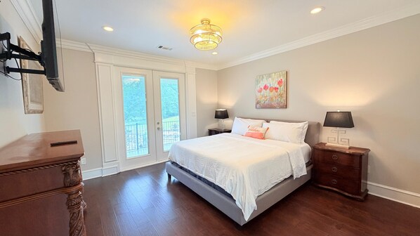 A bedroom with a bed, nightstands, a chandelier, and a painting on the wall.