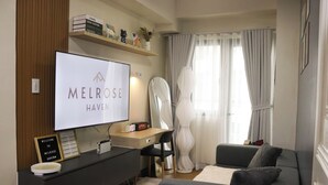 Une chambre d’hôtel moderne équipée d’un téléviseur à écran plat, d’un bureau, d’un canapé et d’une grande fenêtre avec des rideaux.