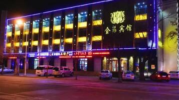 A building with illuminated signage and multiple parked cars in front.