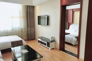A hotel room with a bed, a TV, a coffee table, and a mirror.