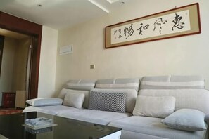A living room with a sofa, a coffee table, and a framed calligraphy piece on the wall. - Jinma Hotel (Qiqihar)