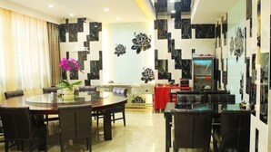 A modern dining area with a round table and chairs, a decorative wall with floral patterns, and a red tablecloth. - Jinma Hotel (Qiqihar)