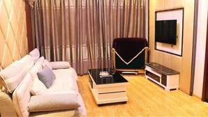 A modern living room with a sofa, a coffee table, a TV, and a chair. - Jinma Hotel (Qiqihar)