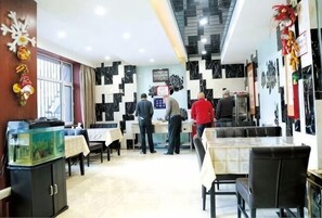 A dining area with tables, chairs, a fish tank, and a patterned wall. - Jinma Hotel (Qiqihar)