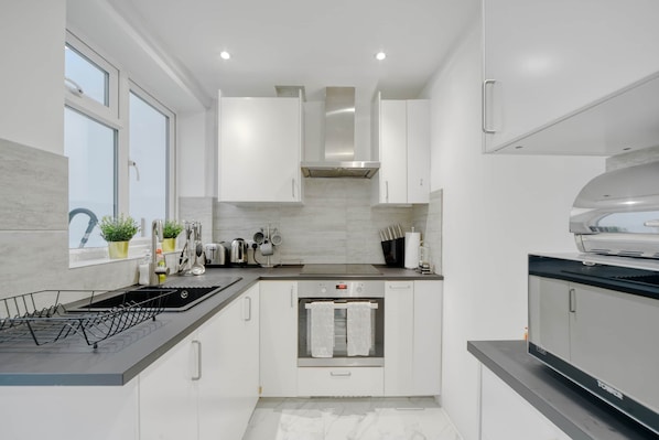Una cucina moderna con mobili bianchi, un forno in acciaio inossidabile e un piano di lavoro nero.