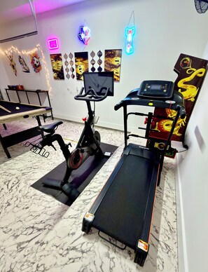 A home gym with a treadmill, stationary bike, and exercise equipment.