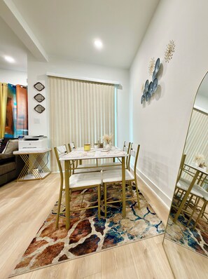 A dining area with a table, chairs, and a patterned rug.