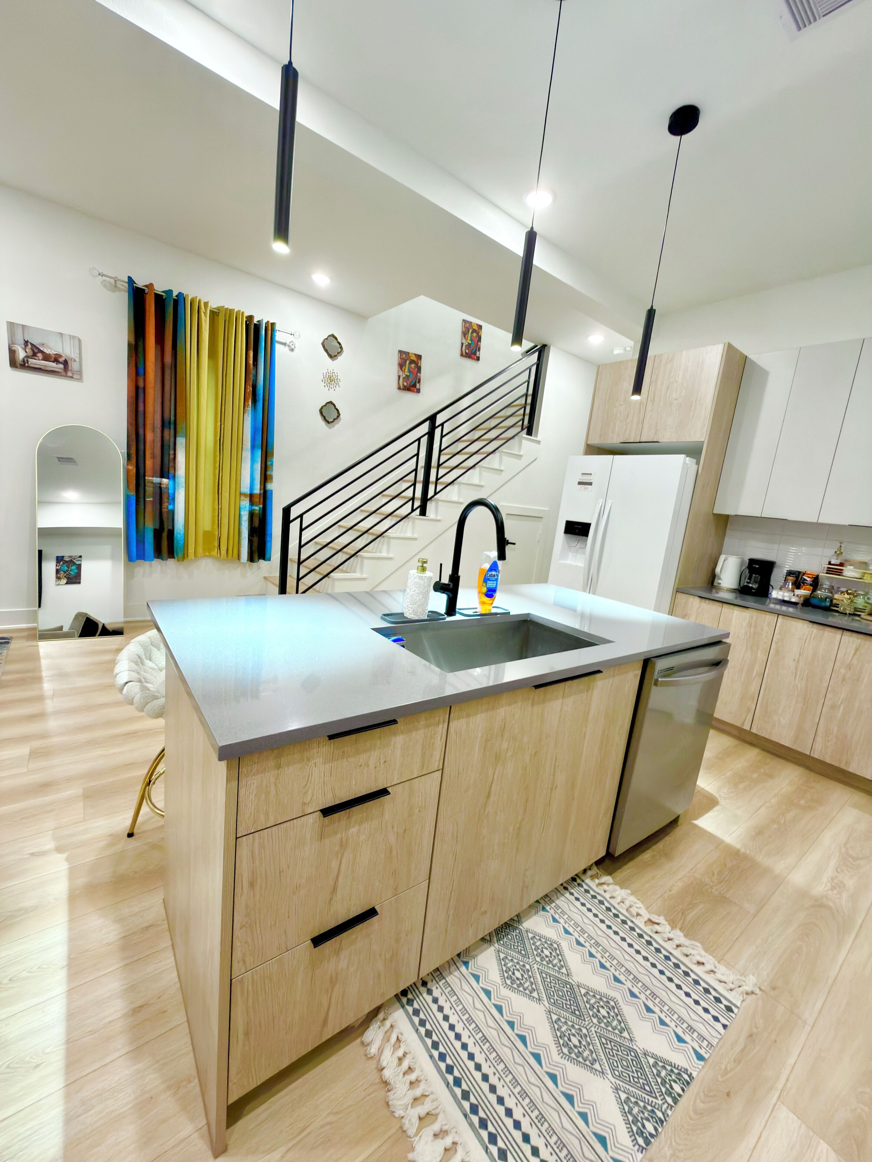 A modern kitchen with a central island, stainless steel appliances, and a wooden cabinet design.
