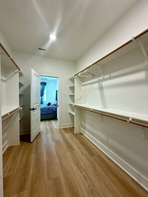 Un couloir doté d’un plancher en bois, de murs blancs et d’une porte donnant sur une chambre.