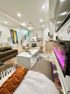 A modern living room with a sofa, coffee table, and a flat-screen TV. - Game Room, Hot tub, Pool table, Gym, Arcade, Grill, Gazebo, 7 min to NRG•MED CTR (Houston)