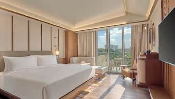 A hotel room with a large bed, a desk, a chair, and a TV.
