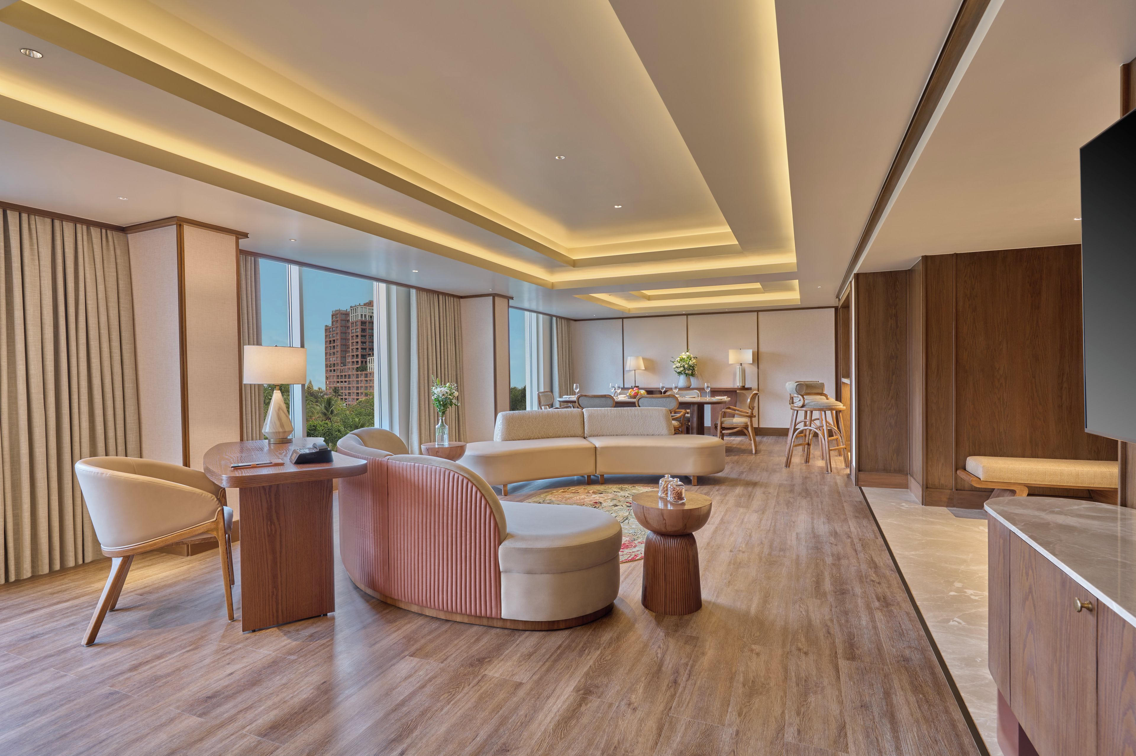 Une chambre d’hôtel moderne dotée d’un grand canapé, d’un coin repas et offrant une vue sur le paysage urbain.