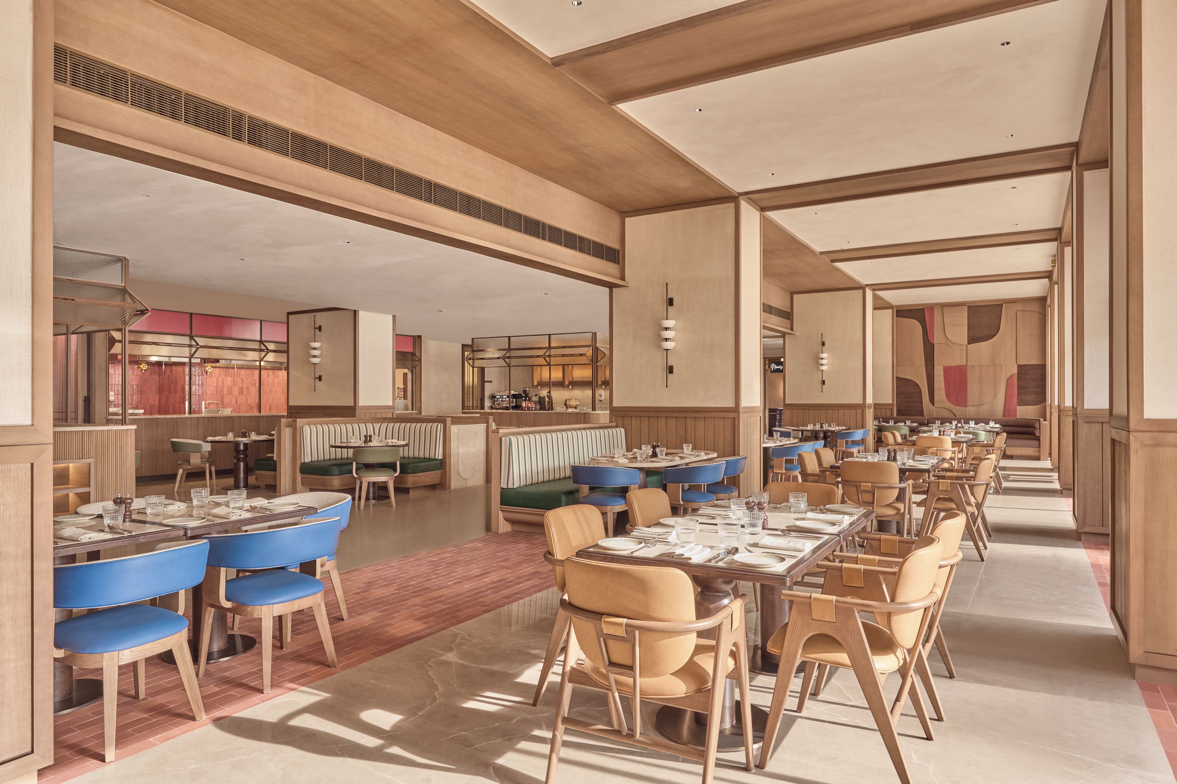 Un restaurant spacieux avec de hauts plafonds, un mobilier moderne et différents types de sièges, notamment des banquettes et des tables.