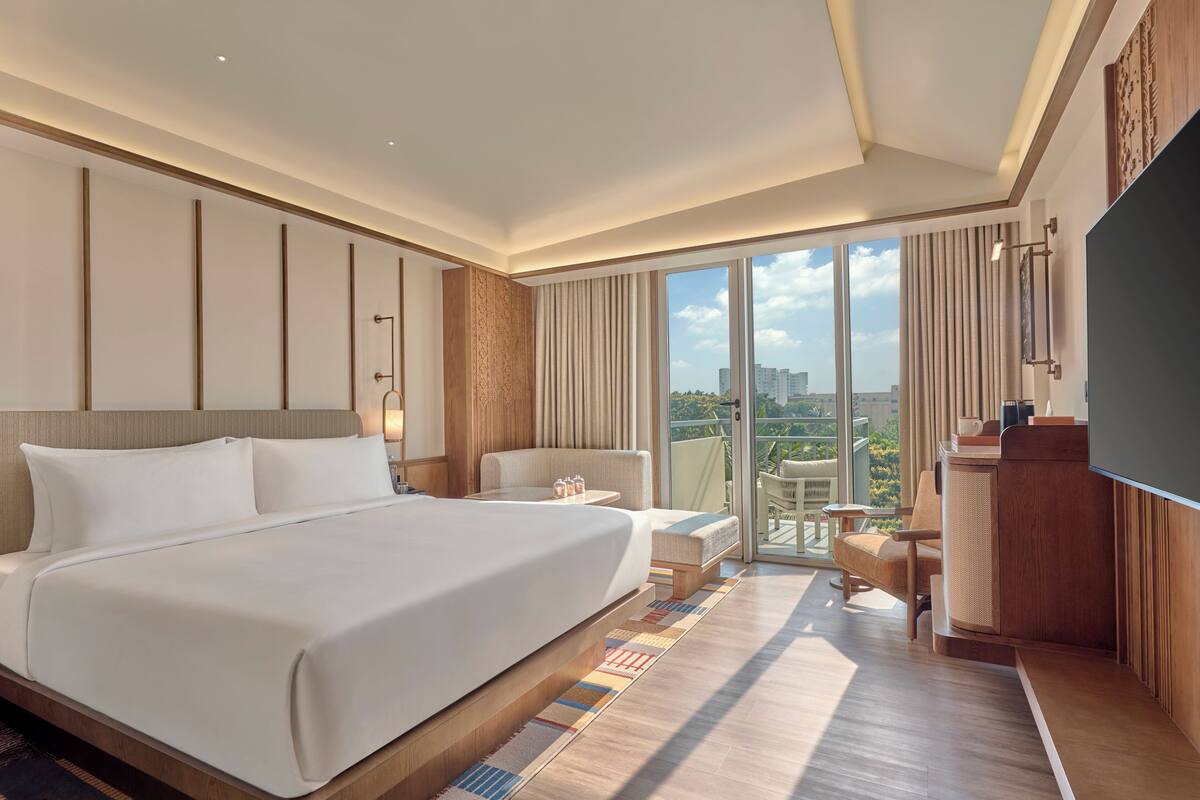 A hotel room with a large bed, a desk, a chair, and a TV.