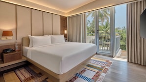 A modern hotel room with a large bed, a nightstand, a lamp, a TV, and a balcony with a view of palm trees. - Slohh by Roach Bengaluru, Curio Collection by Hilton (Bengaluru)