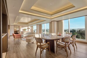 A spacious living area with a large round table, comfortable seating, and a city view.