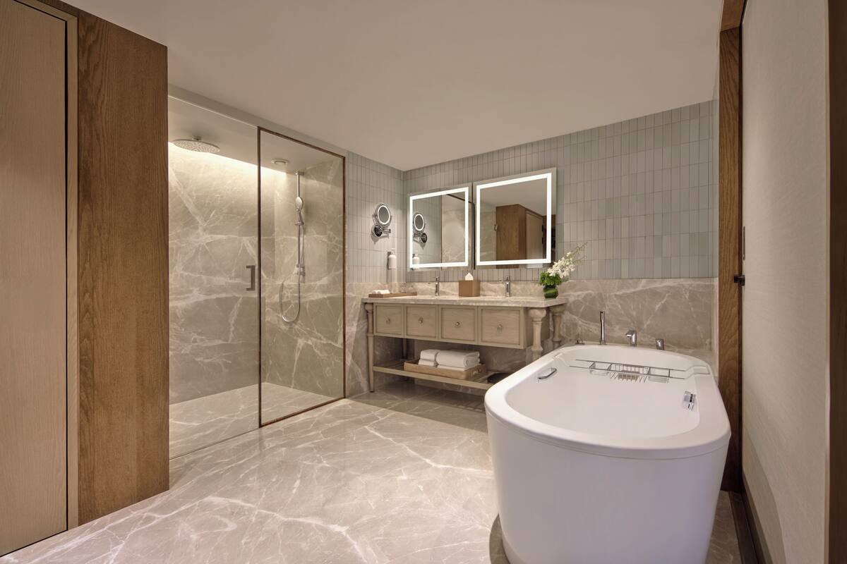 A modern bathroom with a freestanding bathtub, a glass-enclosed shower, and a vanity with a mirror.