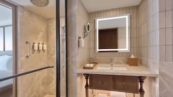 A modern bathroom with a glass-enclosed shower, a vanity with a mirror, and a wooden cabinet below.
