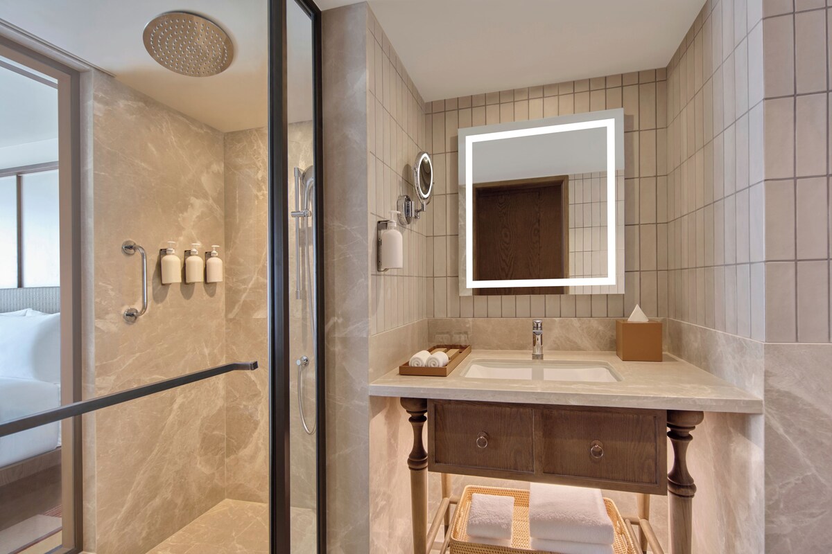 A modern bathroom with a glass-enclosed shower, a vanity with a mirror, and a wooden cabinet.