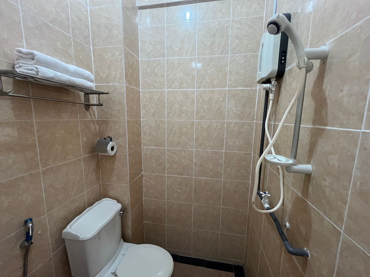 Un baño pequeño con azulejos, un inodoro, un perchero para toallas y una cabina de ducha.