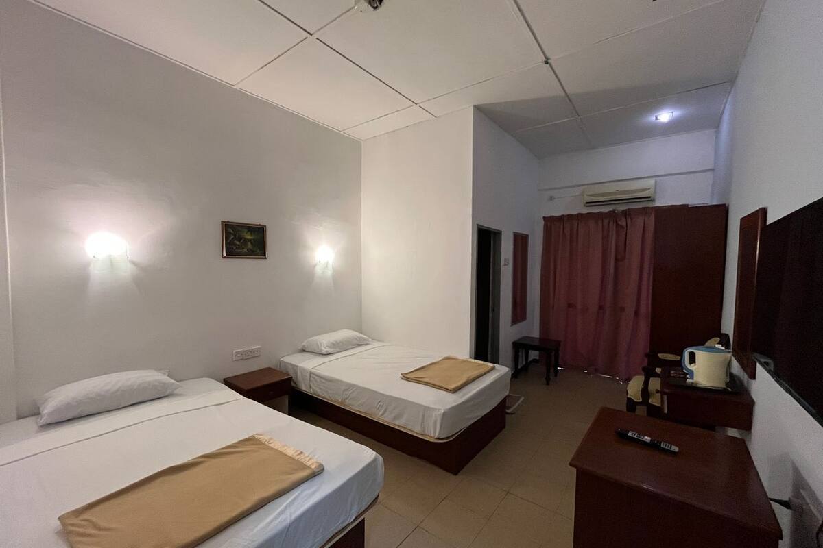 Habitación de hotel con dos camas, un escritorio, una silla y una mesita.