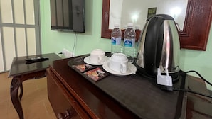 Una habitació amb escriptori de fusta, televisió, mirall i cafetera.