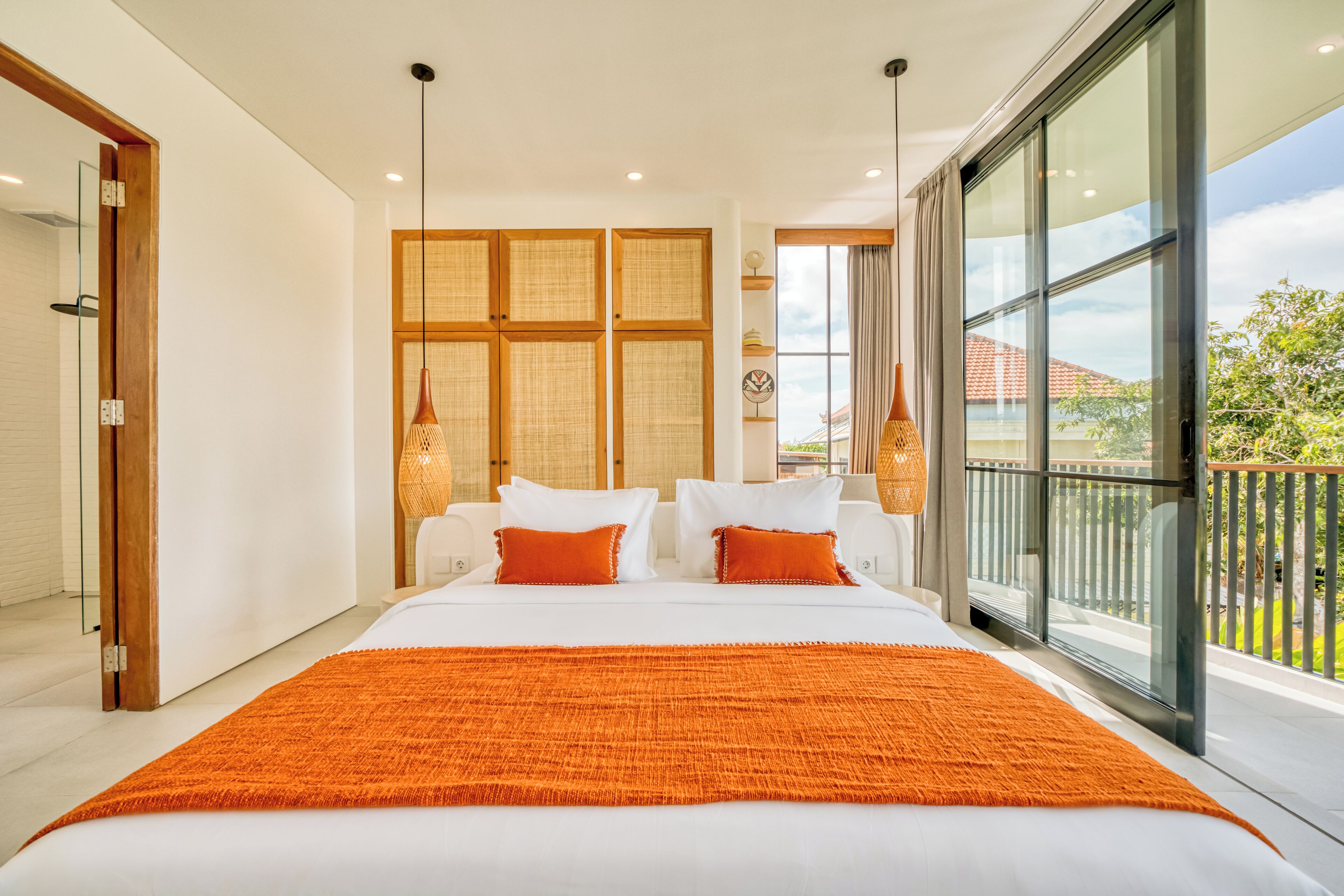 A modern bedroom with a large bed, a view of the outdoors, and a balcony.