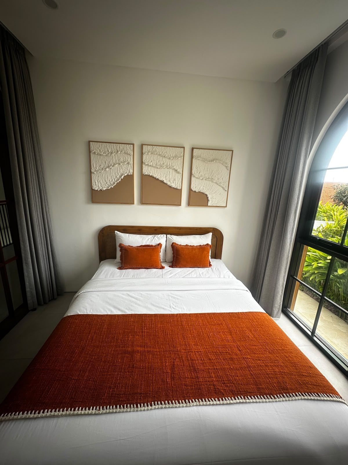 Une chambre avec un grand lit, du linge de lit blanc et une vue sur la verdure par la fenêtre.
