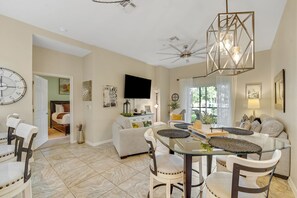A spacious living room with a dining area, a large wall clock, and a ceiling fan. - 1st floor condo near theme parks, gym, tennis court, pools (Davenport)