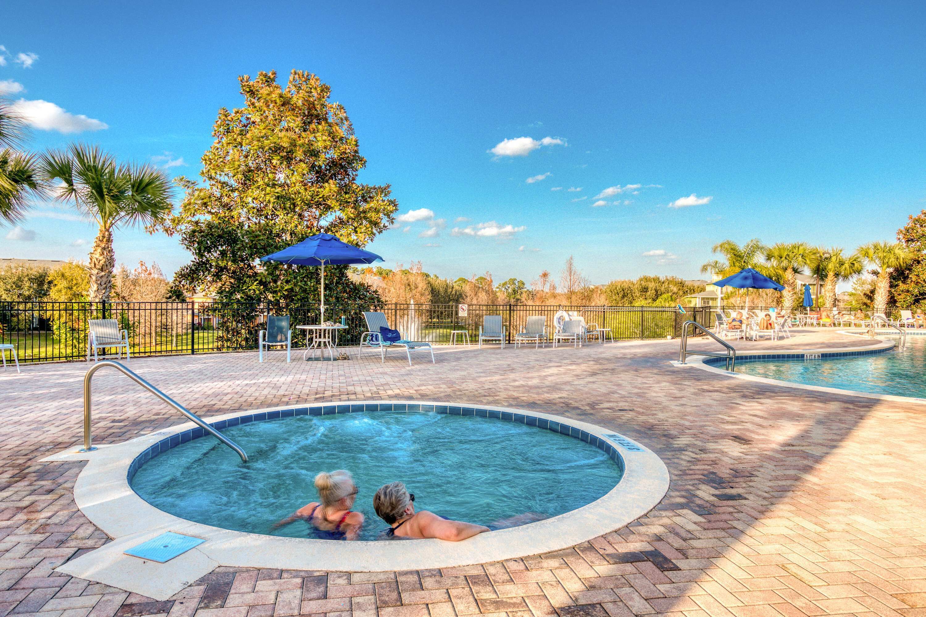 Ein Whirlpoolbereich mit Pool, Liegestühlen und Sonnenschirmen.