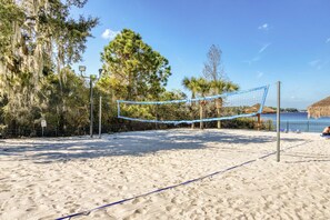 Ein Beachvolleyballfeld mit Netz, umgeben von Bäumen und Blick auf den Ozean.