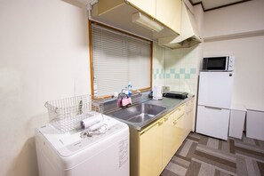 A compact kitchen with a washing machine, a microwave, and a sink. - HOTEL Dorf Komondo (Fukuoka)