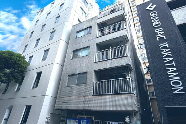 A multi-story building with balconies and a sign indicating "GRAND BAIE KAKATAMON." - HOTEL Dorf Komondo (Fukuoka)
