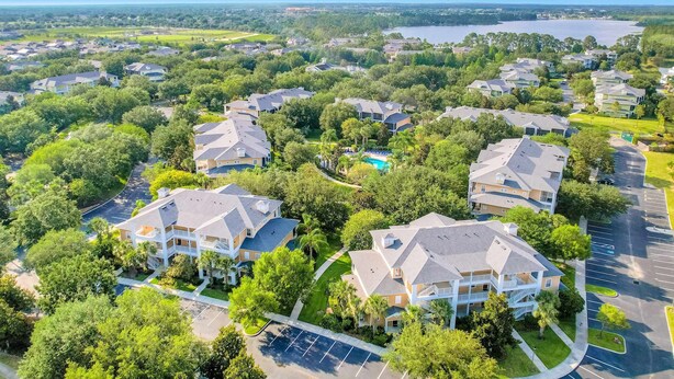 A residential area with multiple houses, a swimming pool, and a lake in the background. - 1st floor condo w/ patio, pools, gym, near theme parks, limited-mobility access (Davenport)