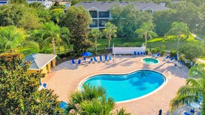 A pool area with lounge chairs and a small pool, surrounded by greenery and a building in the background. - 1st floor condo w/ patio, pools, gym, near theme parks, limited-mobility access (Davenport)