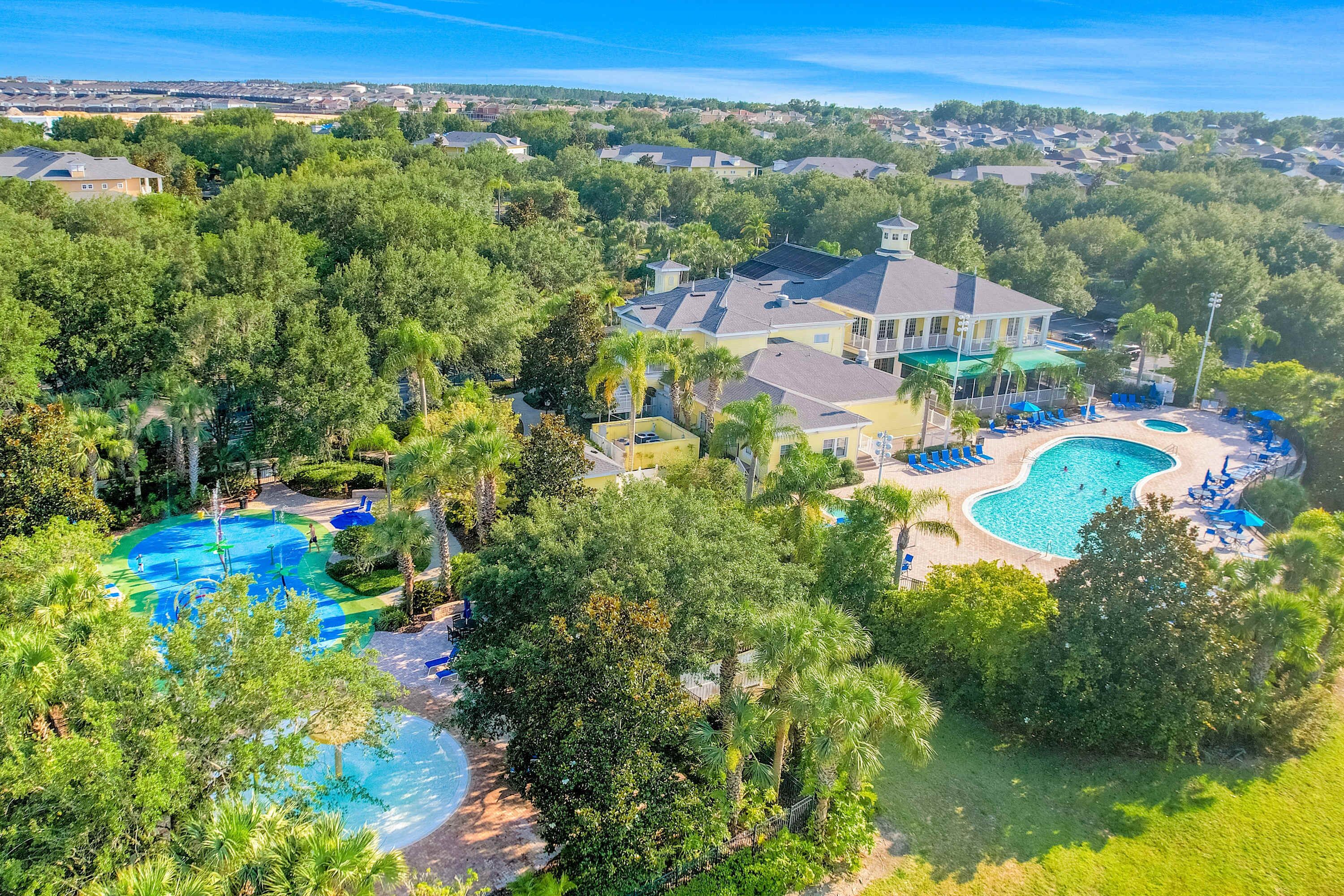 A residential area with a large swimming pool surrounded by lush greenery and a house with a large deck.