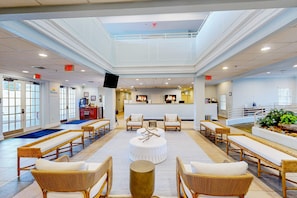 A spacious lobby with wicker furniture, a central round table, and a reception desk. - 3rd floor condo w/ sauna, shared pools, restaurant, gym, balcony (Davenport)