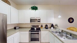 A modern kitchen with white cabinets, stainless steel appliances, and a two-basin sink. - Exclusive 3BR Villa: Pools, Near Disney (Davenport)