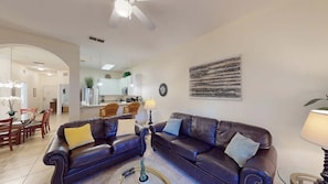 A living room with two leather sofas, a dining area with wooden furniture, and a kitchen in the background. - Exclusive 3BR Villa: Pools, Near Disney (Davenport)