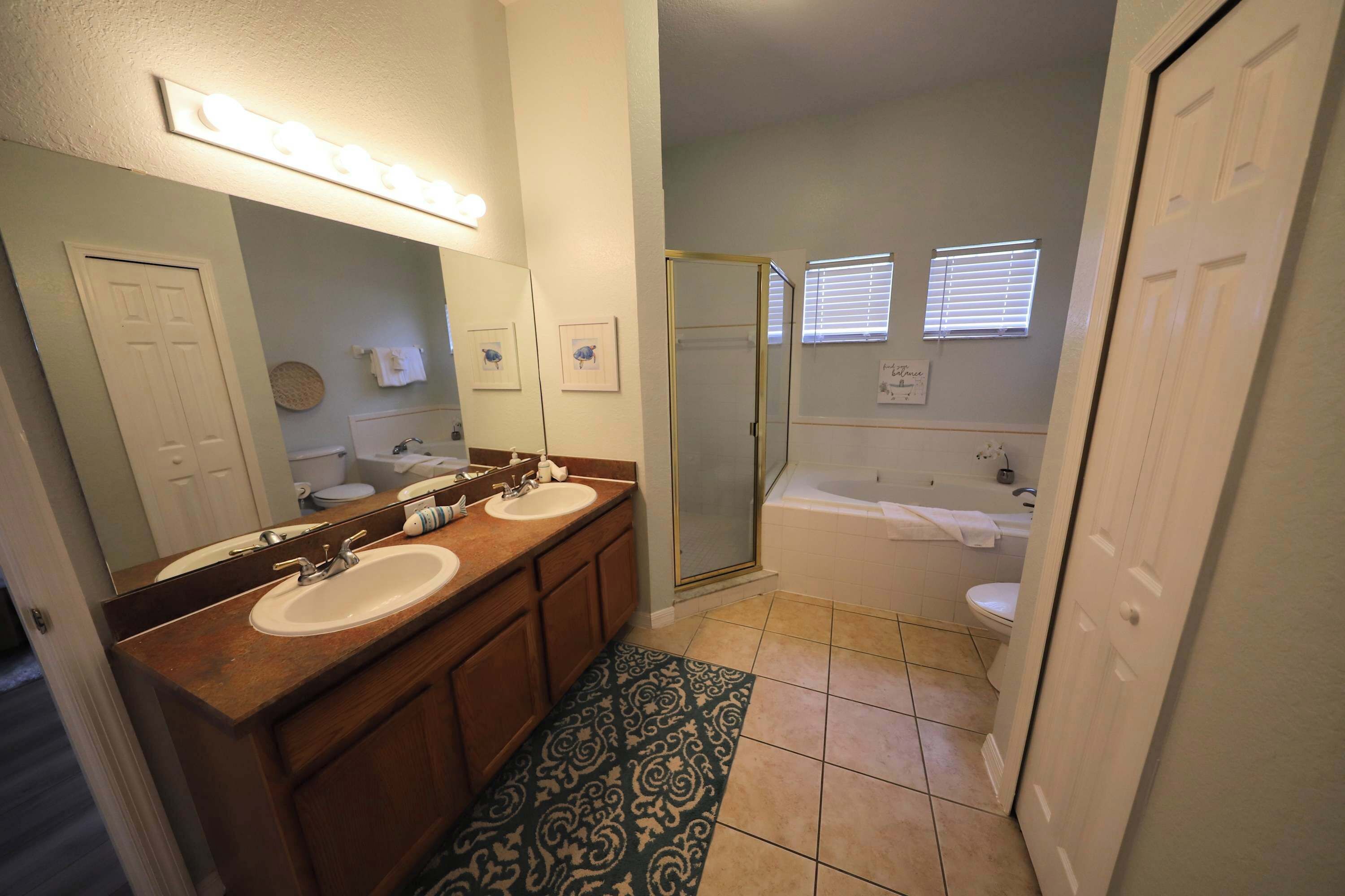 A bathroom with two sinks, a large mirror, a shower, and a bathtub.